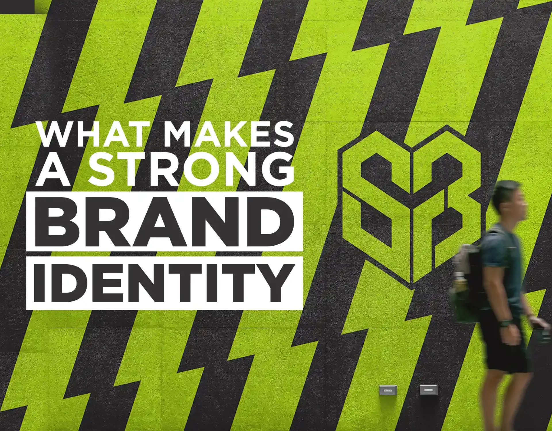 Strong brand identity: what makes a strong brand identity post graphic featuring black and lime green striped wall artwork with bold typography